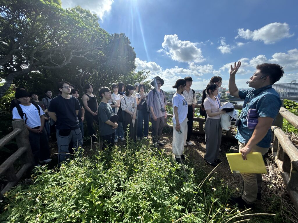 沖縄戦の米軍上陸地点を見学。見晴台ので、学生がガイドの説明を聞いている。